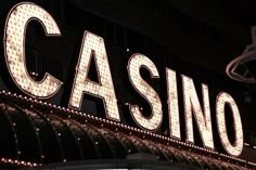 a casino sign lit up at night with the word casino on it's side