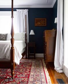 a bedroom with blue walls and white curtains