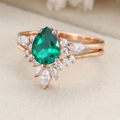 a ring with an emerald and white diamond in the middle, on top of a cushion