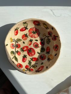 a bowl with tomatoes painted on it sitting on a table