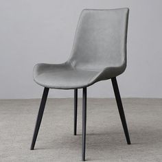 a gray chair with black legs and a white wall in the background, sitting on a carpeted floor