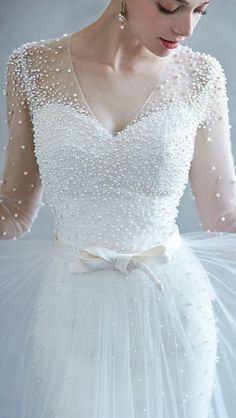 a woman wearing a white dress with pearls on it