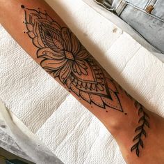 a woman's leg with a tattoo on it that has an intricate flower design