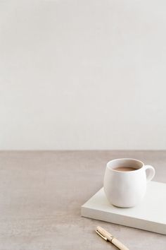 a cup of coffee sitting on top of a table next to a pen