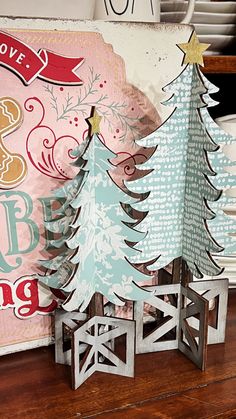 two paper christmas trees sitting on top of a wooden table