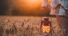 a person standing in a field holding a lantern with the light on it's side