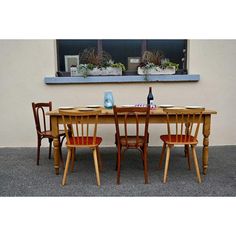 a wooden table with four chairs and a bottle of wine on the table next to it