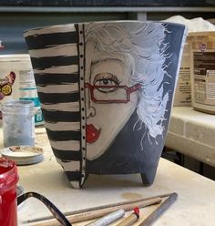 a cup that is sitting on top of a table next to some paintbrushes