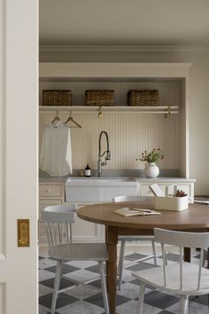 an open door leading to a kitchen and dining area with white cabinets, black and white checkered flooring