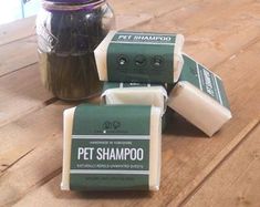 four bars of pet shampoo sitting on top of a wooden table next to a jar