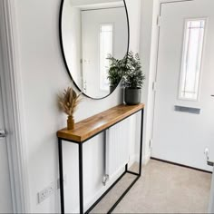 a mirror sitting on top of a wooden shelf next to a plant in a vase