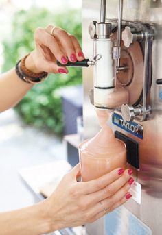 a woman is filling a drink into a glass in front of a machine that has the word taylor on it