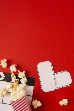 popcorn and movie ticket on red background with white paper cut out to look like an arrow