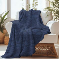 a blue blanket sitting on top of a white chair next to a potted plant