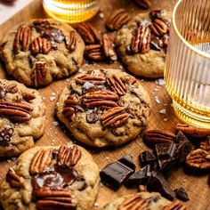 chocolate chip cookies with pecans and caramel on a cutting board next to a glass of whiskey