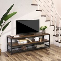 a flat screen tv sitting on top of a wooden entertainment center next to a stair case