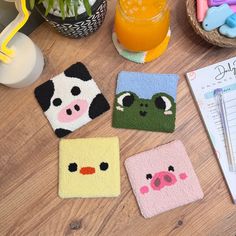 four coasters with animals on them sitting on a table next to a notepad and pen