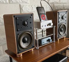 two speakers sitting on top of a wooden table next to a speaker with an mp3 player