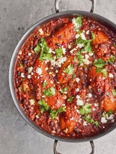 a pot filled with chili and cheese on top of a counter next to a spoon