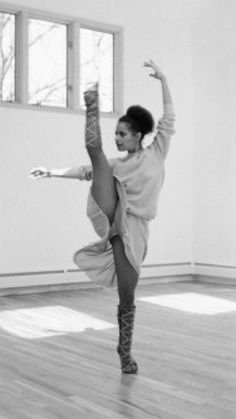 a woman is doing a dance move in an empty room with wood floors and windows