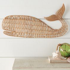 a decorative fish made out of wicker sitting on top of a wooden table next to a coconut