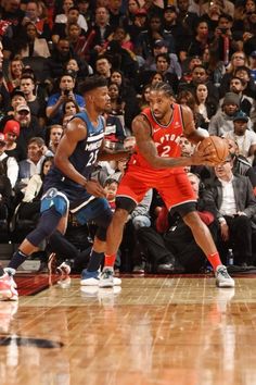 two basketball players are playing on the court while people watch from the stands watching them