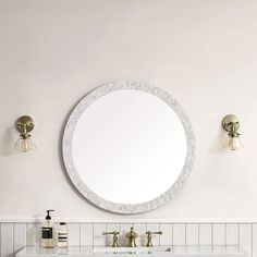 a bathroom vanity with a round mirror above it and two faucets on the wall