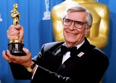 an older man holding up his oscar statue