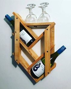 three wine glasses and two bottles in a wooden holder on a white wall with the bottom half open