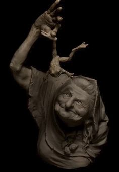 a clay sculpture of a woman holding an animal on her head and hands in the air