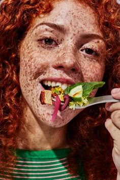 a woman with freckles on her face eating a salad