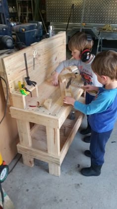 two young boys working on a wooden work bench