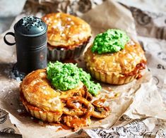 three pastries with green toppings and a cup of coffee on a piece of paper