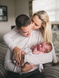 a man and woman holding a baby in their arms