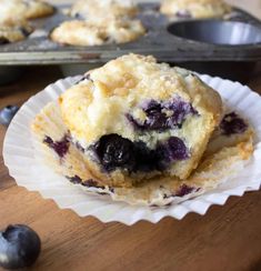 blueberry muffins sitting on top of a paper plate next to a muffin tin