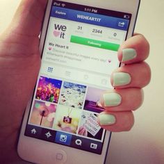 a person holding up a cell phone with white nails on their fingers and the screen showing pictures