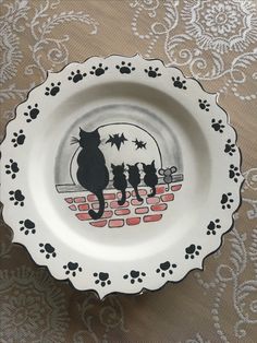 a black cat sitting on top of a white plate