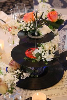 there is a cake made out of records and flowers on top of the table with candles