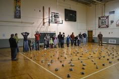 a group of people standing on top of a basketball court covered in lots of silver objects