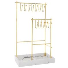 a gold and white marble display rack with rings on the top, two hooks hanging from it's sides