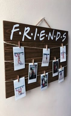 a wooden sign hanging on the wall with photos hung to it's sides and friends written on them