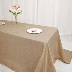 there is a table with a cloth on it and flowers in a vase next to the table