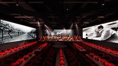 an empty auditorium with red chairs and large screens