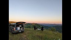 an suv parked on top of a lush green hillside