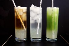 three different colored drinks in tall glasses with straws on the top and one is green