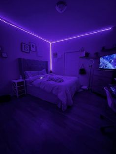 a bed in a room with purple lights on the walls and a flat screen tv