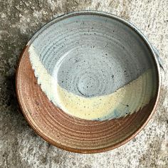 a brown and white bowl sitting on top of a cement floor next to a wall