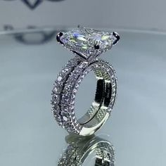 an engagement ring with a princess cut diamond in the center and two rows of diamonds on each side