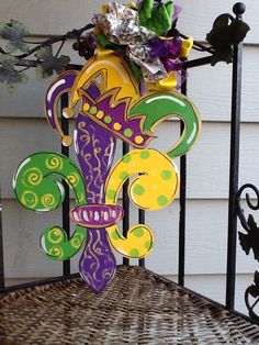 a colorful sculpture sitting on top of a metal chair next to a wall with flowers in it