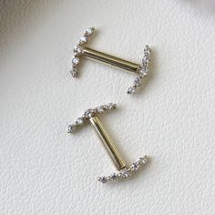 two gold and diamond ear clips on a white surface